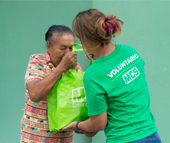 Participante del Mindful Community Program de MCS entregando alimentos a adulta mayor en comunidad de Puerto Rico.